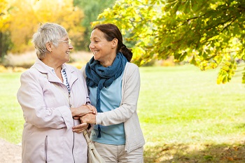 middle age woman and senior woman walking through a park on a sunny day