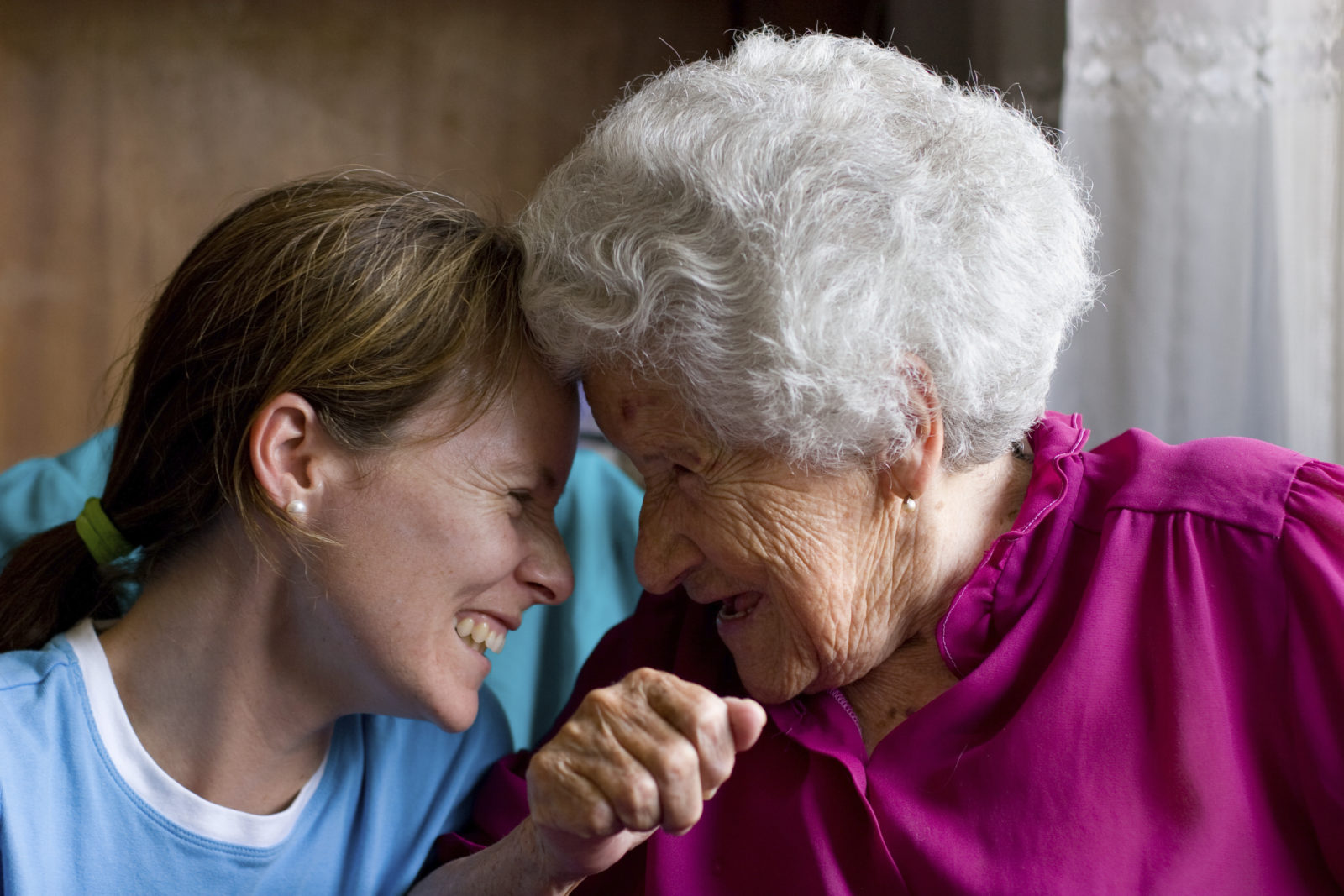 middle age woman and senior woman touching foreheads and smiling at each other