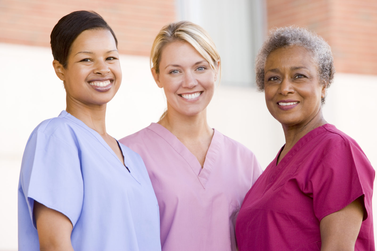 three women dressed in medical scrubs smiling for photo