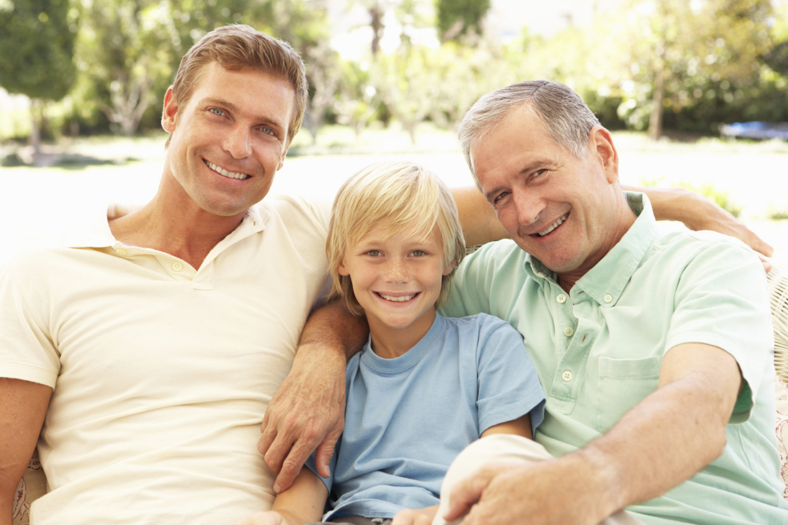 grandfather, son, and grandson sitting outside smiling for photo