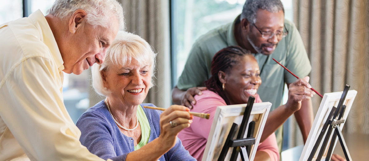 group of seniors smiling during a painting class