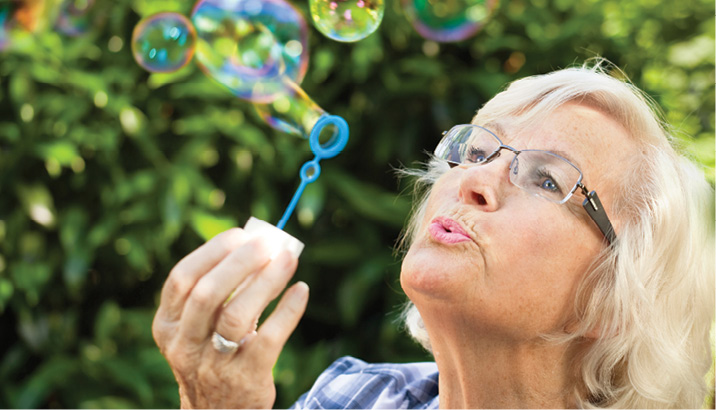 mature woman blowing bubbles outside on a sunny day