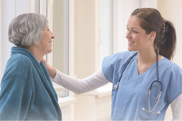 Young female nurse talking with senior woman in hospital