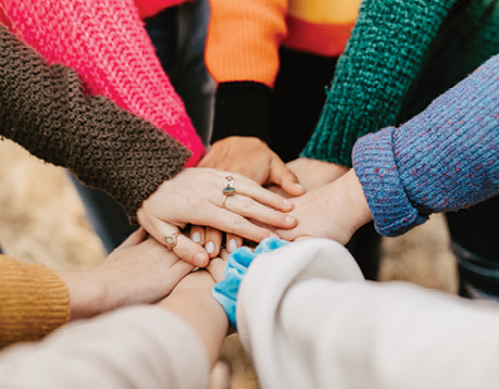 group of individuals putting their hands together signifying working together