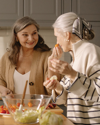 two mature women cooking happily together in a kitchen
