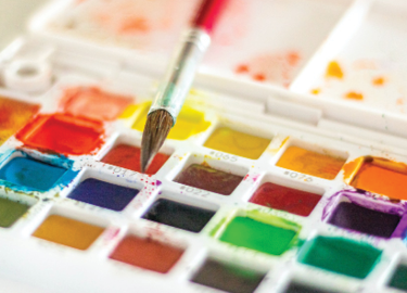 close up image of vibrant watercolors and paint brush