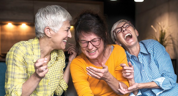 group of three older adult women laughing together on couch