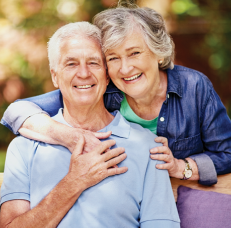 older adult woman leaning over older adult man in an embrace for photo