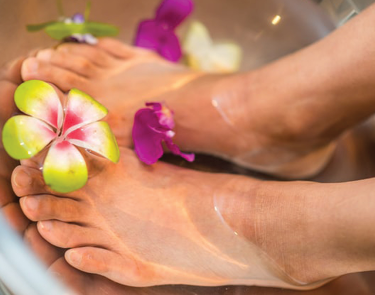 portrait of a woman's feet soaking in a bath with flowers