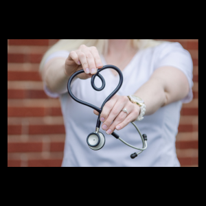 nurse wearing white scrubs holding heart shaped stethoscope