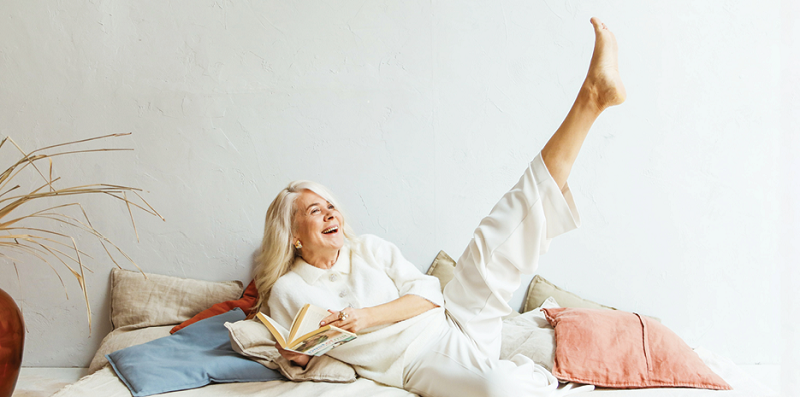 woman smiling, kicking leg in air and holding a book