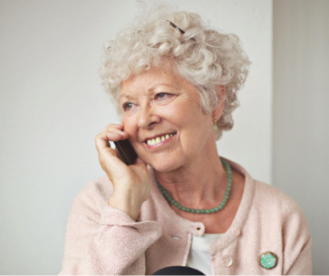senior woman, in pink blouse, talking on the phone with a friend.