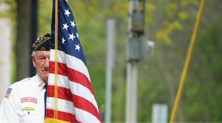 war veteran holding US flag during memorial day ceremony